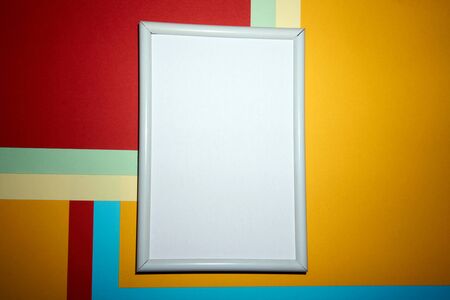 Colorful geometric texture paper pattern in yellow, blue, red, green with a picture frame in white.の写真素材