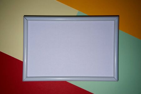Colorful geometric texture paper pattern in yellow, blue, red, green with a picture frame in white.の写真素材