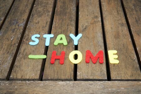 Stay at home, alphabet letter, on a wooden plate as a background.の写真素材