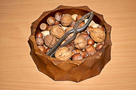 Almonds, walnuts and hazelnuts in wooden bowls on wooden background.