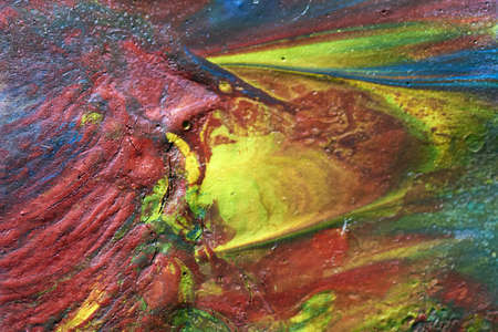 Macro shot of a mix of acrylic paint and oil on a marbled paper background.