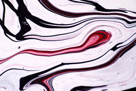 Macro shot of a mix of acrylic paint and oil on a marbled paper background.