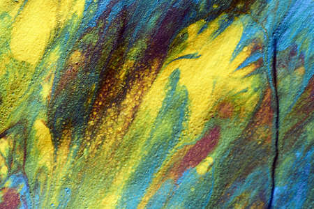 Macro shot of a mix of acrylic paint and oil on a marbled paper background.