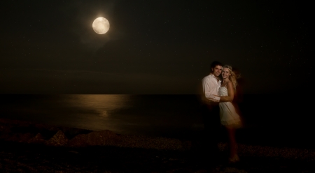 Romantic newly-married couple kissing at the beach under moonlight during  summer vacation.の写真素材