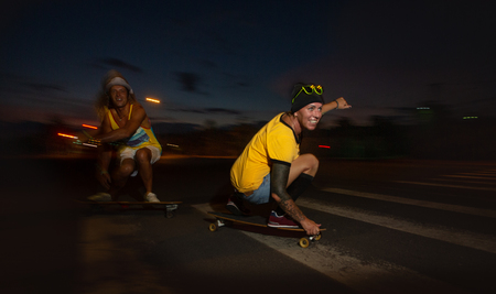 Skateboarders ride skateboards at nightの写真素材