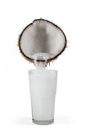 Coconut with flowing juice in a glass. Isolated on white background.の写真素材