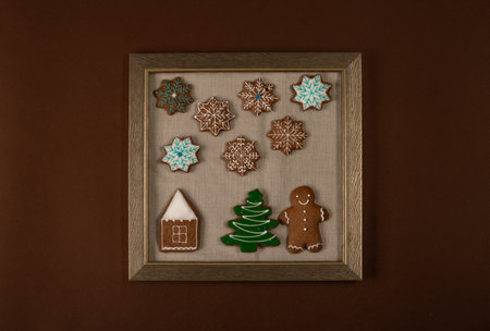 Frame with Christmas ginger cookies on brown wall