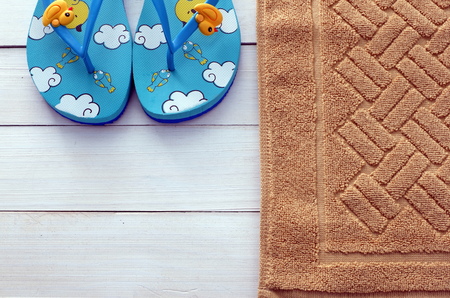 Flip flops  and brown carpet mat in front of bathroom on white wooden floorの写真素材