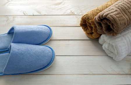 Blue soft slipper and three of towel in front of bathroom on white wooden floorの写真素材