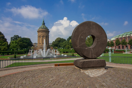 The Wheel sculpture against Fountains at Friedrichsplatz with Mannheim Water Tower against skyの写真素材