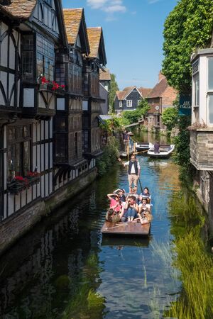 CANTERBURY, UK, - JULY, 11, 2019: Tourists enjoy a punt ride on the River Stour as they pass the...