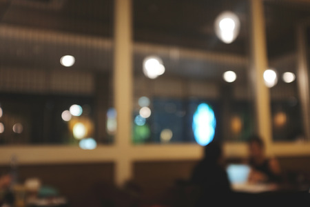 Blurred background image of modern coffee shop. abstract blur background with people in cafe. warm color tone styleの写真素材