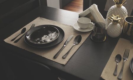 a set of set plates cutlery on black wooden dinner table with with Prop. copy spaceの写真素材