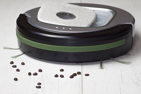 Automatic vacuum cleaner on white floor panels that cleans coffee beans and other impurities that require daily cleaning.の写真素材
