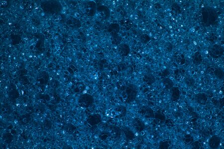 Kitchen sponge in dark blue color used mainly for washing dishes, in close-up shot.の写真素材