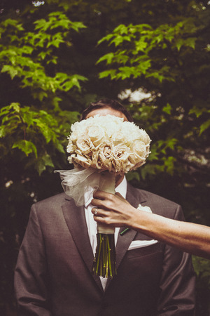 Bride hides groom with her flower bouquetの写真素材