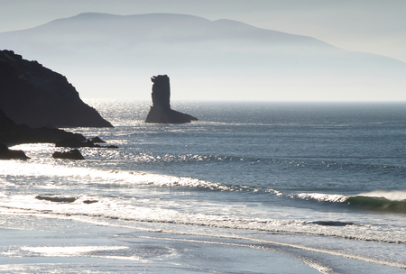 early morning sunlight burns mist and fog from kerry coastlineの写真素材