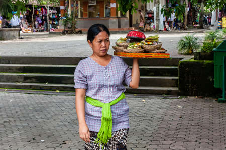 A Balinese woman selling fruits to touristsのeditorial素材