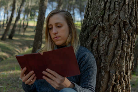 Young woman resting and reading an e-book in the woodの写真素材