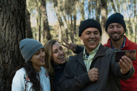 Group of latin friends doing a video call during a trekking dayの写真素材