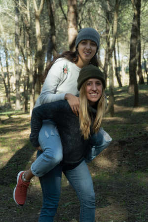 Woman giving piggyride to another in the woodの写真素材