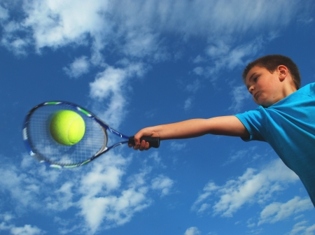 tennis. A little boy hitting a forehand shot with racketの写真素材