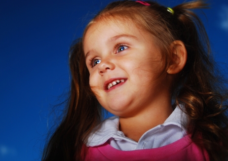 Happy little girl with long wild hair smiling outsideの写真素材