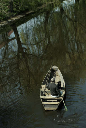 Man and dog canoeing down a peaceful river.の写真素材