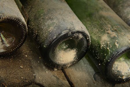 Close up of three bottles in a cellar covered with dust, bottoms of the bottles covered with dirt, special lightingの写真素材