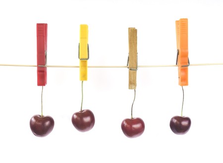 Four ripe cherries with clothespins on a clothesline, isolated on white backgroundの写真素材