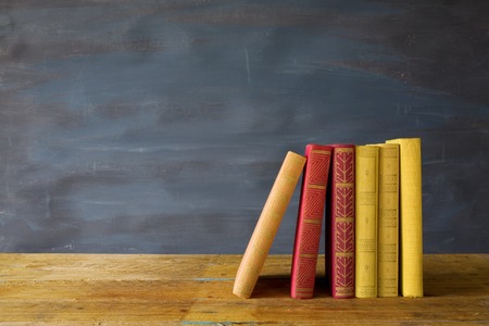 row of books, on blackboard background, free copy space
