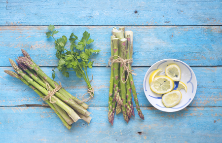 Fresh green asparagus, parsley and lemons, free copy space, flat layの写真素材