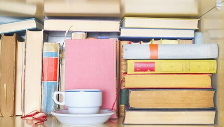 Books in a book shelf with cup of coffee and spectacles . Reading, learning, education, literature...
