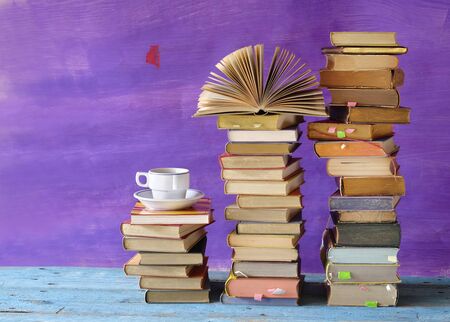 Stacks of multicolored books and an open book plus a cup of coffee. Reading, education, literature, learning, relaxing, book fair concept の写真素材