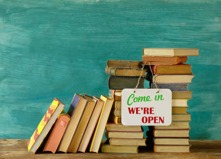 Reopening bookshops after the lock down, stack of books and open sign,symbolicの写真素材