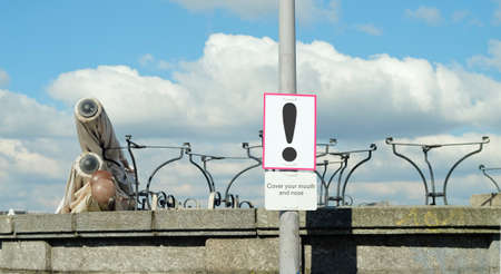 Gastronomy  lockdown, closed restaurant and warning sign. Stacked tables and folded sun shades outdoors, symbolic pictureの写真素材