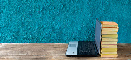 Stack of books and laptop computer,home office, homeschooling,reading,education, business concept. Free copy space,teal background, panoramicの写真素材