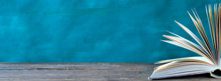 Open book, hardback books on wooden table on teal background. Back to school,education,reading. Copy spaceの写真素材