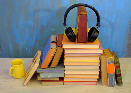 audio book concept, with stack of books, headphones and cup of coffee