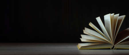 Open book, hardback book on wooden table on dark background. Back to school, education, reading....