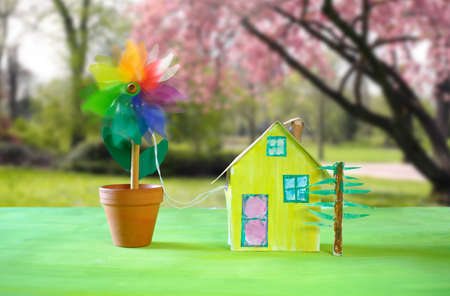 cute model home with wind turbine, clean energy,low carbon power concept. Blurred beautiful landscape in the background.の写真素材