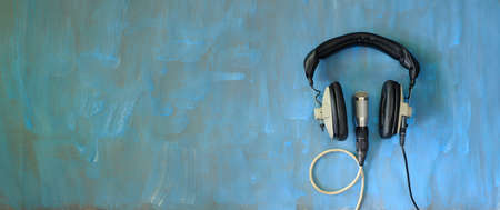 Podcasting concept, vintage headphones and recording microphone on grungy blue backgroundの写真素材
