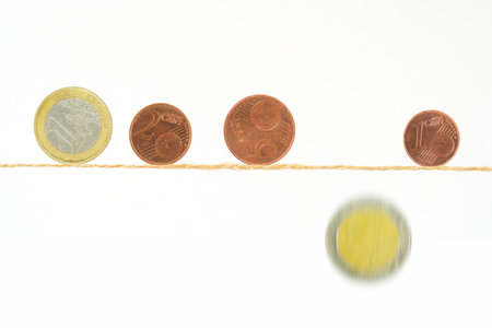 Coins of Euros balancing on a thin rope, one is falling down,financial crisis, inflation,danger of poverty concept.の写真素材