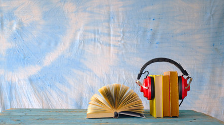 audio book concept with row of books, one opened and vintage headphones,panoramic, free copy spaceの写真素材