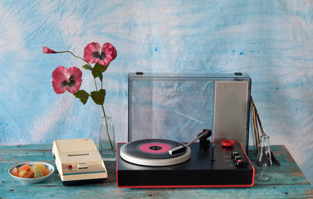 vintage turntable with purple vinyl record, speaker and old cassette tape recorder, seventies still...