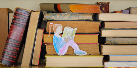 education,learning,knowledge concept,books on a shelf with drawing of a girl reading a bookの写真素材