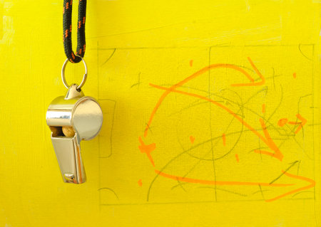 Whistle of soccer referee or coach and soccer tactics scribble on yellow background,close up.の写真素材