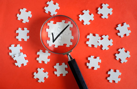 Magnifier enlarging the correct or check mark on jigsaw puzzle pieces. Business quality control and approval and contract assignment concept.の写真素材