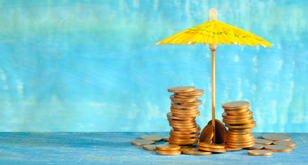 Wealth management or rising prices for vacation concept, heap of coins and sun umbrella, free copy spaceの写真素材