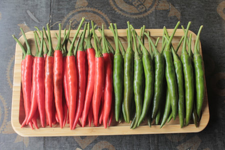 Red and green chilli peppers in wooden tray on wooden table.の写真素材